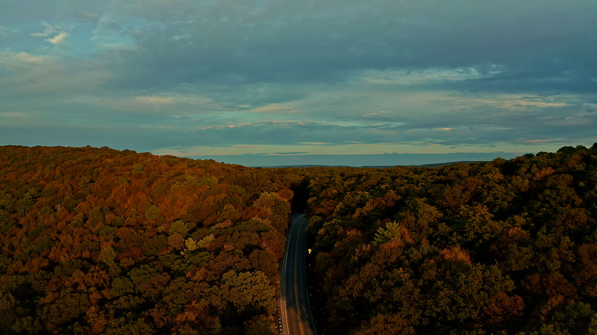 Drone shot of road passing over ridge in fall